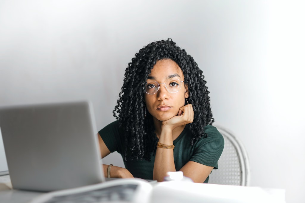 Disengaged officer worker with black curly hair sitting at her desk