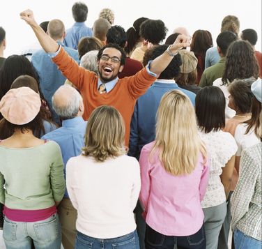 Crowd of people around happy smiling black man with his arms extended up