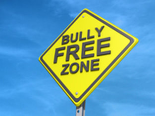 Yellow street sign says 'Bully Free Zone', with blue sky behind