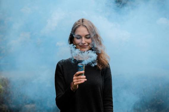Woman holding a smoke bomb, showing a person who would be difficult to get along with